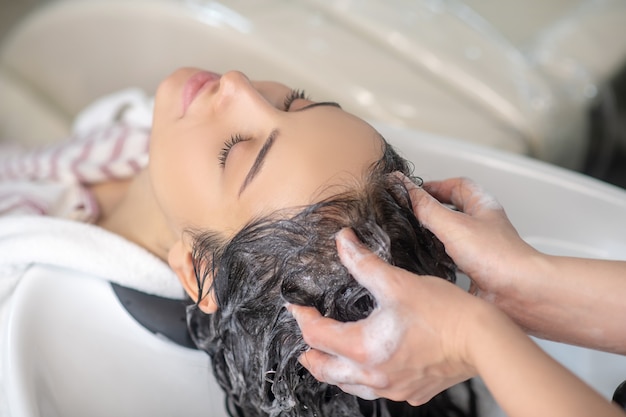 Kapper. Vrouw gevoel ontspannen terwijl haarstylist haar haren wast