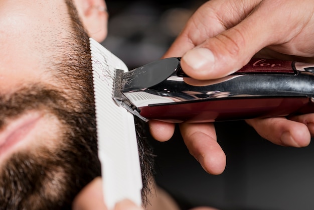 Kapperhand van de kapperige man met elektrische trimmer