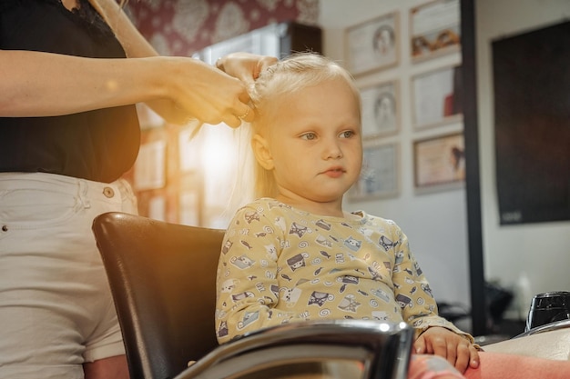 Kappersvrouw maakt modieus mooi kapsel voor schattig klein blond meisje