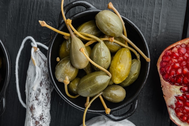 Kappertjes, gemarineerde kappertjes, op zwarte houten tafel, plat gelegd