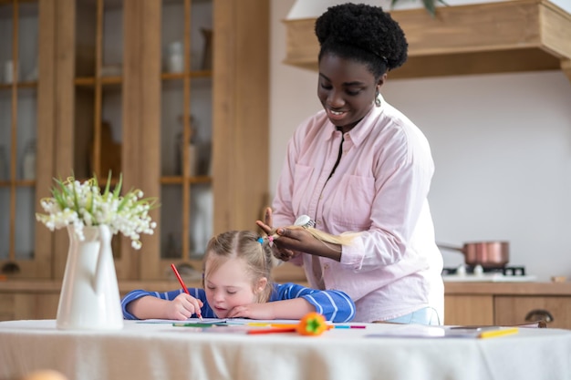 Kapsel. Een vrouw die achter het meisje staat en haar haar doet