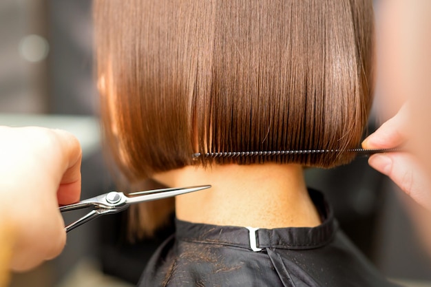 Kapsel van kort haar van jonge blanke vrouw door handen van een kapper in een achteraanzicht van een kapsalon close-up