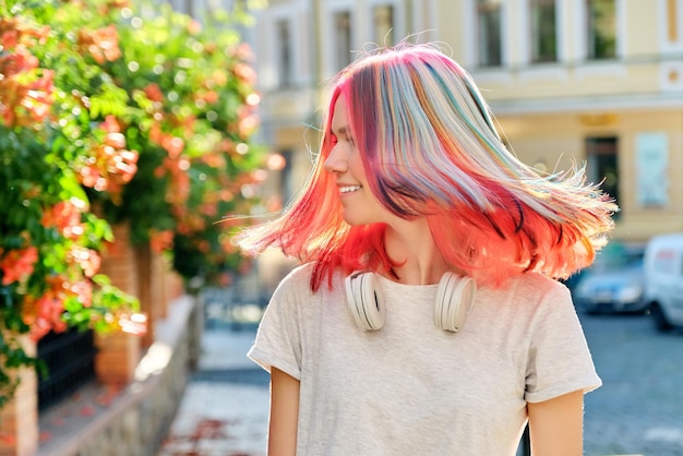 Kapsels, haren, mode, trends, kleuren. Close-up van fladderend gekleurd geverfd haar van jonge vrouw op zonnige stadsstraat