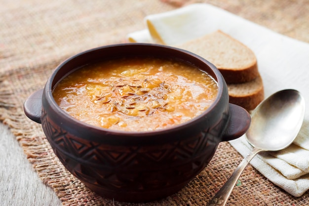 Капустняк - традиционный украинский зимний суп с квашеной капустой, пшеном и мясом в деревенской посуде.