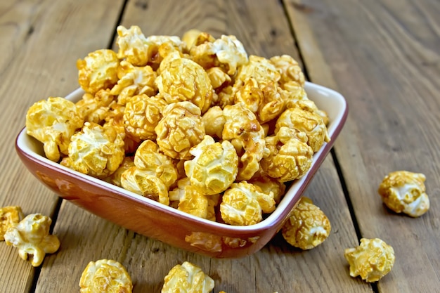 Karamelpopcorn in een kleikom op een houten plankenachtergrond