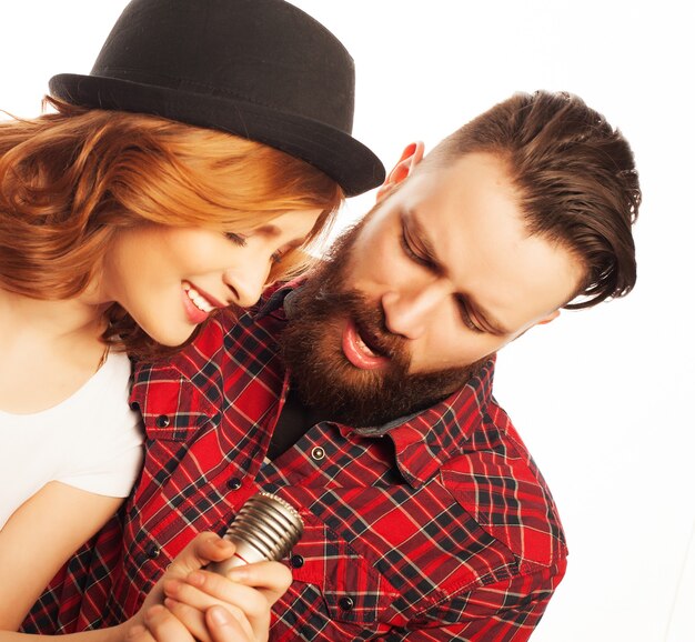 Karaoke - Lovely couple with microphone. Young and beauty. Hipster style. Over white background.