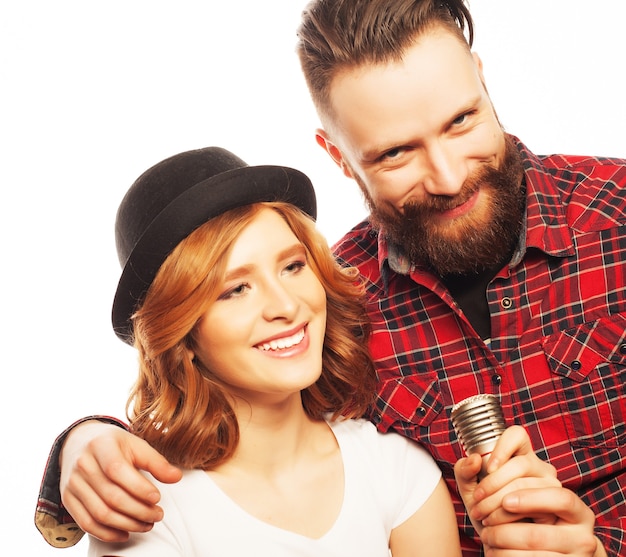 Karaoke - Lovely couple with microphone. Young and beauty. Hipster style. Over white background.