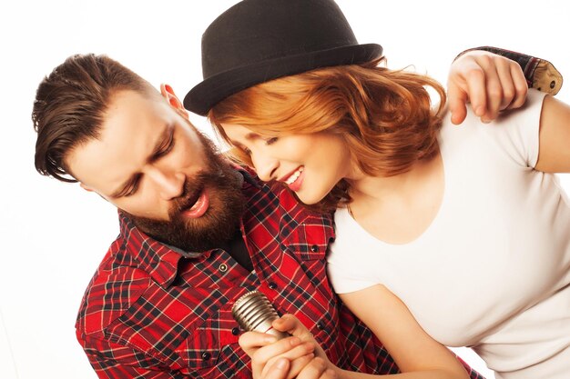 Karaoke - Lovely couple with microphone. Young and beauty. Hipster style. Over white background.
