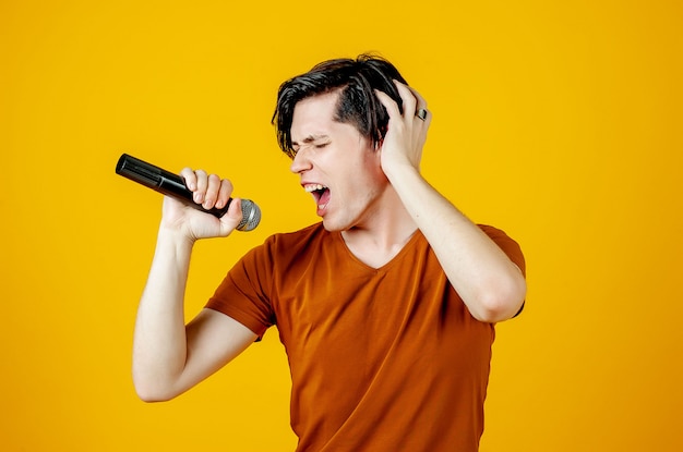 Karaoke man singing a song into a microphone, on a yellow background. A funny man holds a microphone in his hand at the karaoke singer singing a song! Pivets on a yellow background