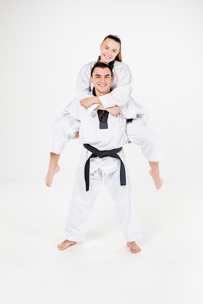 La ragazza e il ragazzo di karate in kimono bianco e cintura nera in posa su sfondo grigio.