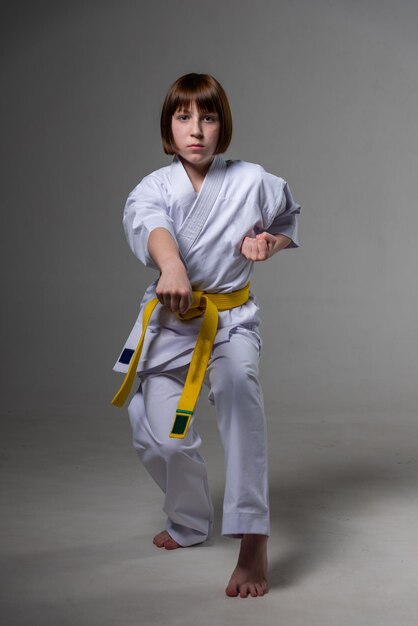 A karate girl trains in a kimono with punches and kicks