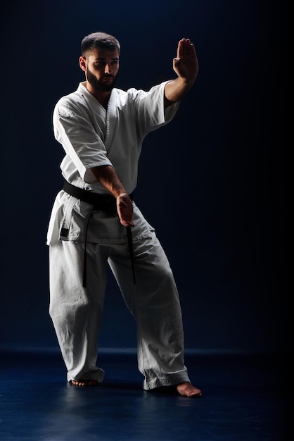 Karate man in een kimono in vechthouding op een blauwe achtergrond