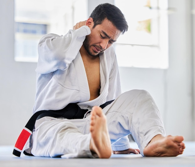 Karate sports injury and neck pain of man at fitness club for martial arts exercise and training to fight for competition athlete male tired after taekwondo sport and training with health problem