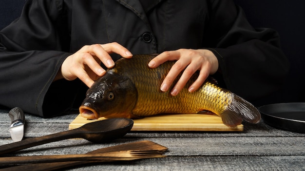 Karper verse vis koken met een open mond op een snijplank op een zwarte houten tafel