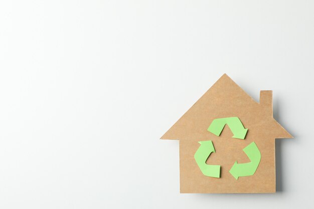 Kartonhuis met recyclingsteken op witte achtergrond, ruimte voor tekst