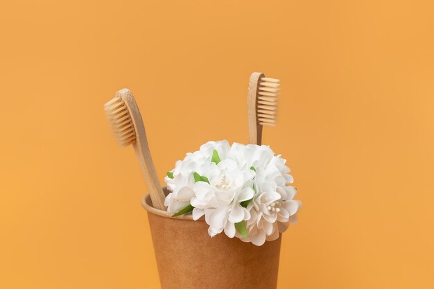 Kartonnen beker met bamboe tandenborstels en bloemen op een beige achtergrond