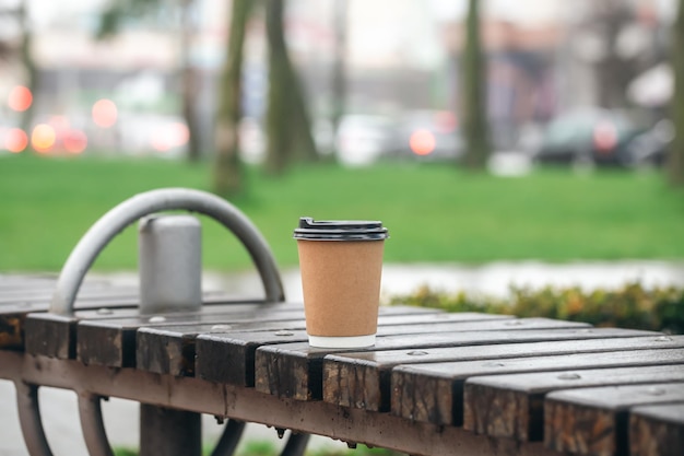 Kartonnen beker op houten bankje in park kopie ruimte