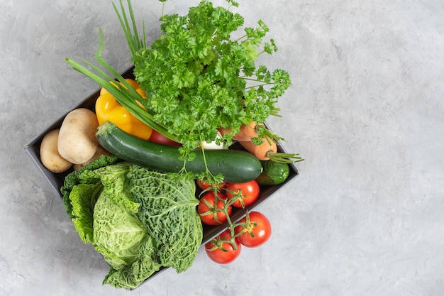 Kartonnen doos vol verse biologische groenten van de lokale markt op grijze tafel