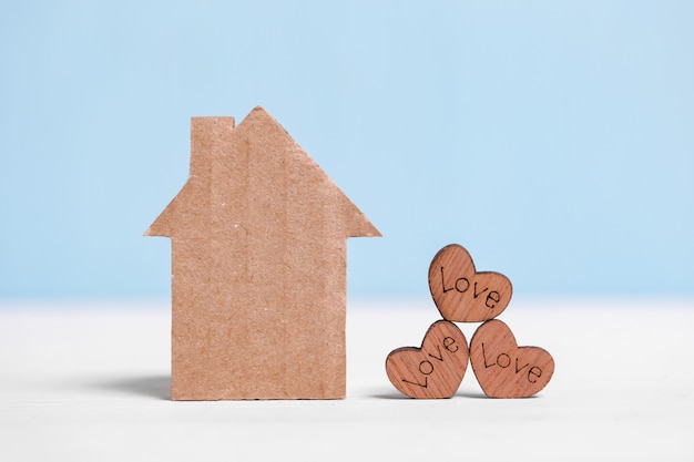 Kartonnen huis en houten harten met inscripties Liefde op blauw en wit.