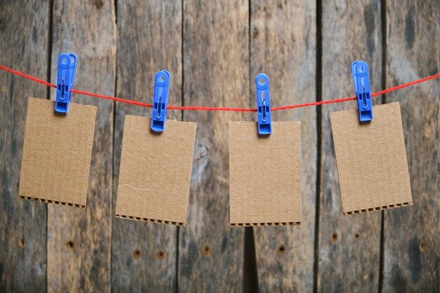 Foto kartonnen kaarten worden met wasknijpers op een houten achtergrondsjabloon gehangen voor inscriptie