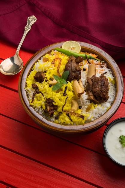 Kashmiri Mutton Gosht of Lamb Biryani bereid in basmatirijst geserveerd met yoghurtdip over humeurige achtergrond, selectieve focus