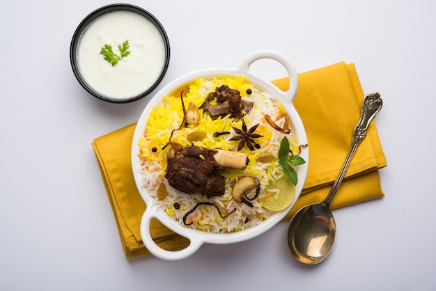 Kashmiri Mutton Gosht of Lamb Biryani bereid in basmatirijst geserveerd met yoghurtdip over humeurige achtergrond, selectieve focus