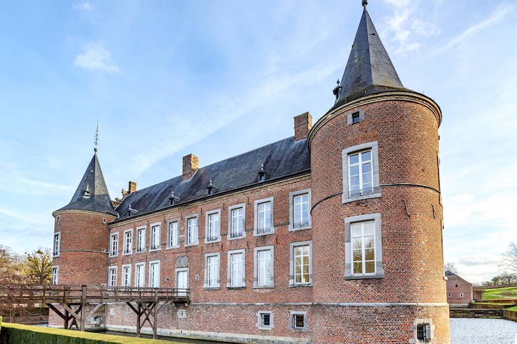 Foto kasteel alden biesen uit de 16e eeuw, omringd door de gracht, houten brug, ronde toren, bakstenen muren, ramen en zadeldak, uitzicht vanaf de binnenplaats, bewolkte dag in bilzen, limburg, belgië