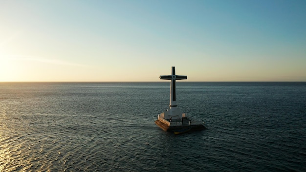 Katholiek kruis in een gezonken begraafplaats in de zee bij zonsondergang luchtdrone