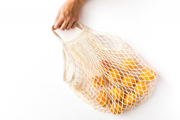 Katoenen eco mesh tas met seizoensgebonden fruit abrikozen op witte achtergrond.