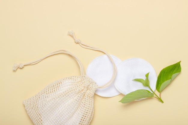 Katoenen herbruikbare make-up remover pads in een stoffen zak op een beige achtergrond Het concept van ecologie en bewuste consumptie Herbruikbare wattenschijfjes