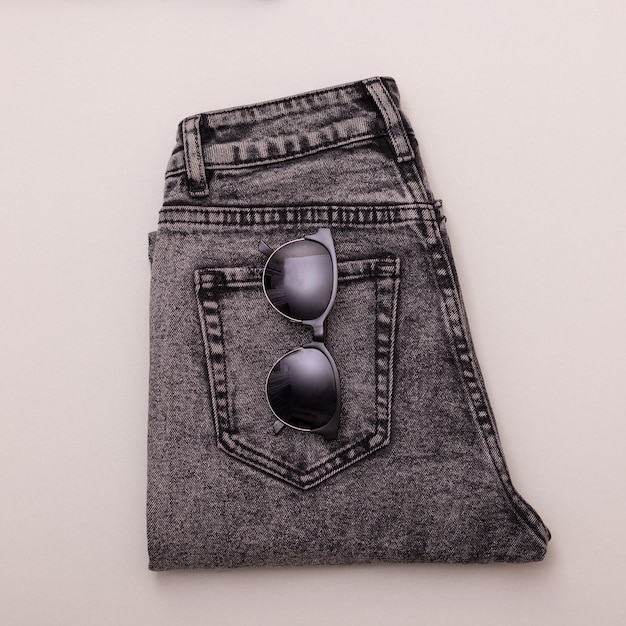 Katoenen jeans en zwarte glazen plat liggende foto