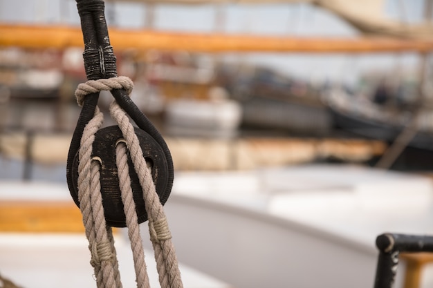 Katrol voor zeilen en touwen gemaakt van hout op een oude zeilboot, met zeil en andere boten onscherp