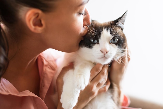 Katteneigenaar dame kuste haar mooie pluizige vriend binnenshuis close-up