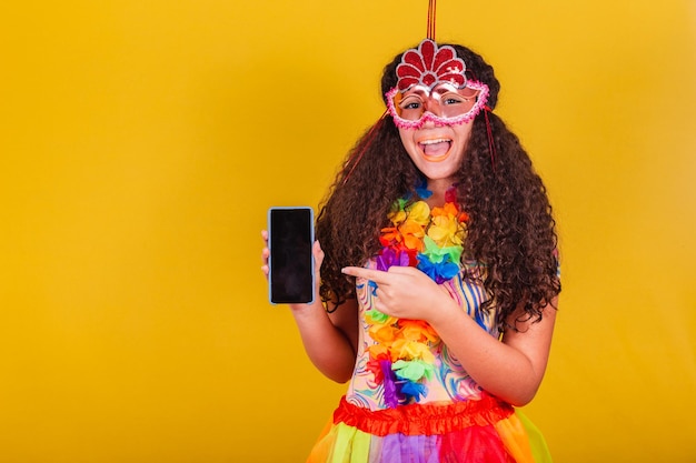 Kaukasisch Braziliaans meisje gekleed voor carnaval wijzend naar mobiele scherm app verbonden wereld