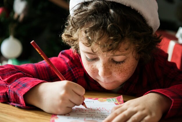 Kaukasisch jong geitje dat een wenskaart van Kerstmis schrijft