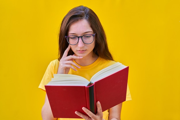 Kaukasisch jong meisje dat met lang donkerbruin haar een rood boek leest