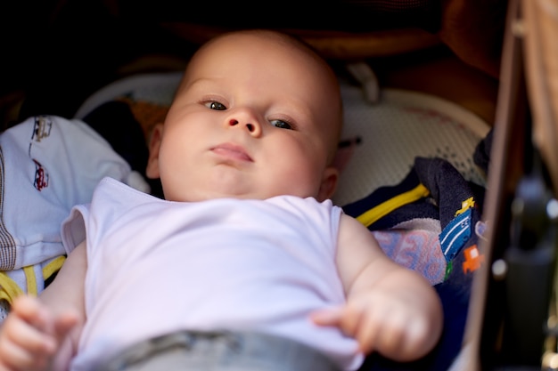 Kaukasisch jongetje ligt in kinderwagen tijdens het wandelen buiten