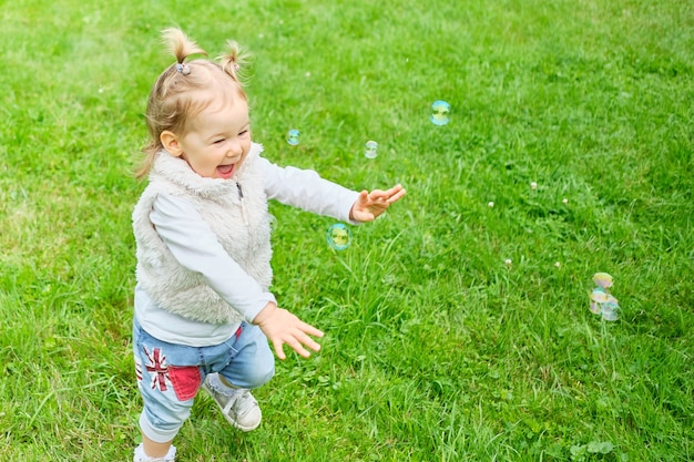 Kaukasisch kind gelukkig rennen na zeepbellen