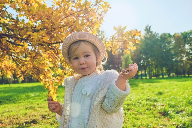 Kaukasisch kind meisje in rustieke kleding loopt met een hoed in de herfst park.