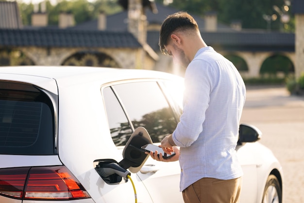 Kaukasisch mannetje koppelt elektrische auto los van laadstation man trekt netsnoer los