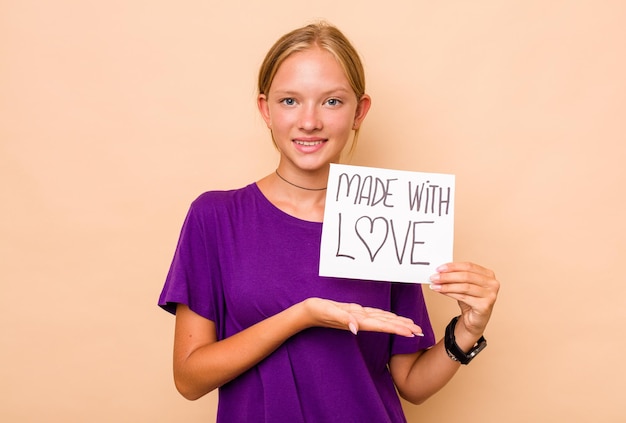 Kaukasisch meisje bedrijf gemaakt met liefde plakkaat geïsoleerd op beige achtergrond