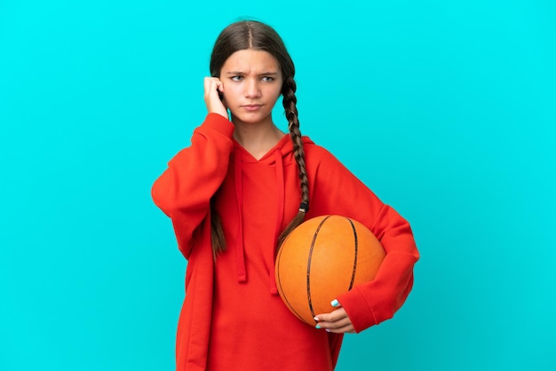 Foto kaukasisch meisje dat basketbal speelt geïsoleerd op blauwe achtergrond gefrustreerd en oren bedekt