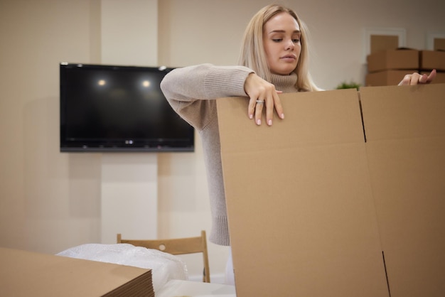 Foto kaukasisch meisje dat dozen plakt om in een nieuw appartement te verhuizen