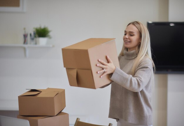 Foto kaukasisch meisje dat dozen plakt om in een nieuw appartement te verhuizen