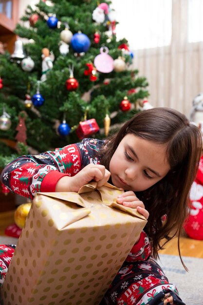 Kaukasisch meisje dat een kerstcadeau thuis opent. Ruimte voor tekst.