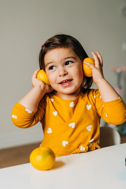 Kaukasisch meisje dat pret met mandarijnen heeft. Gezond kinderdieet. Immuunversterking met vitamine c. Hoge kwaliteit foto