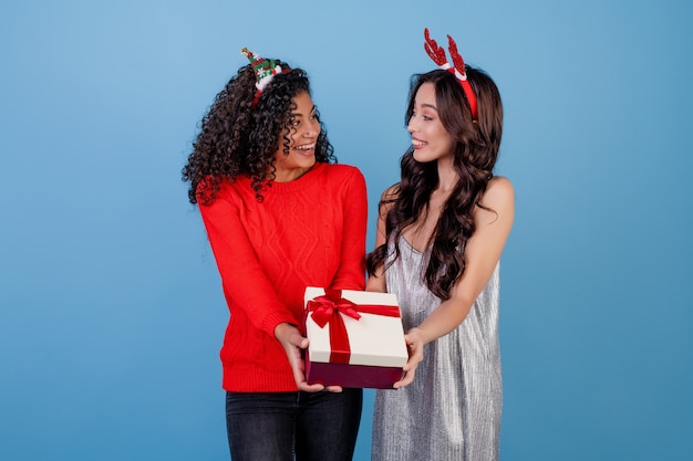 Kaukasisch meisje en zwarte met giftdoos die over blauw wordt geïsoleerd