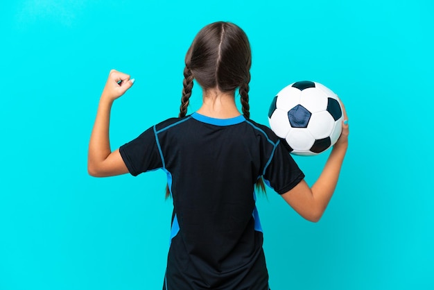 Kaukasisch meisje geïsoleerd op blauwe achtergrond met voetbal