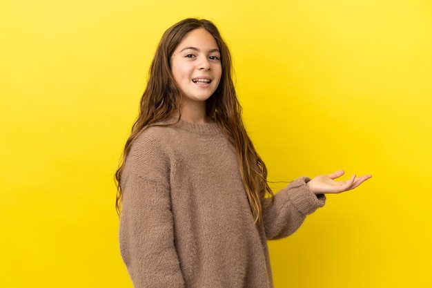 Kaukasisch meisje geïsoleerd op een gele achtergrond die de handen naar de zijkant uitstrekt om uit te nodigen om te komen