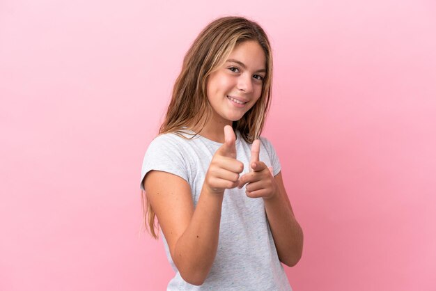 Kaukasisch meisje geïsoleerd op een roze achtergrond die naar voren wijst en glimlacht